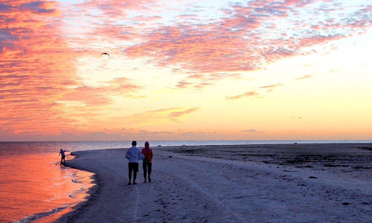 couple walking on beach at sunset