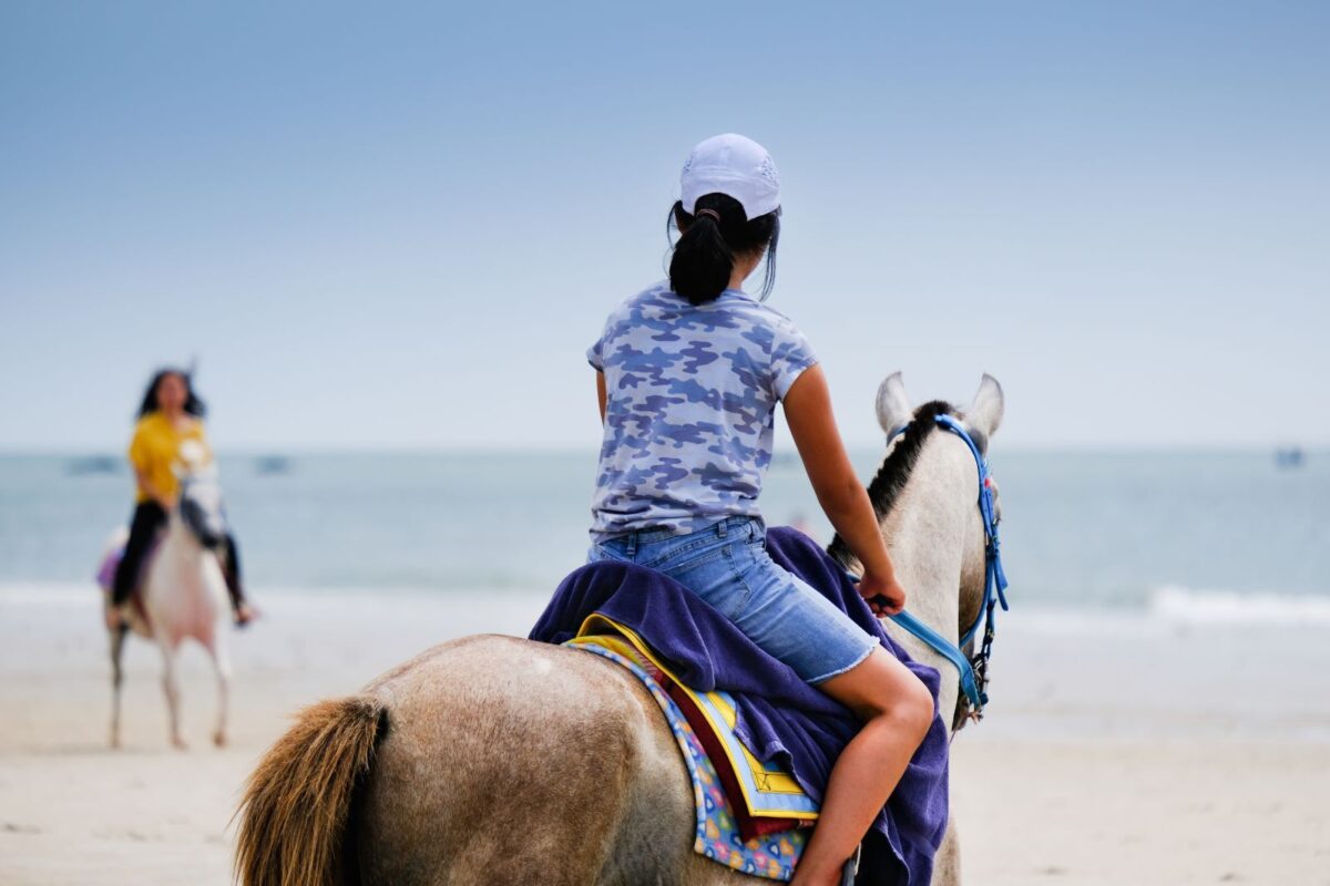 girls riding horses on the beach